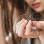 Woman experiencing hair fall while holding hair strands, consulting a Skin Specialist Pimpri Chinchwad for treatment and care